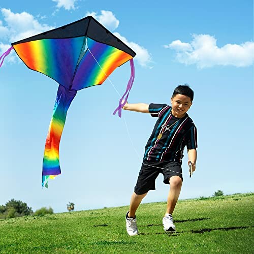 Boy running while flying a colorful kite on a grassy field.